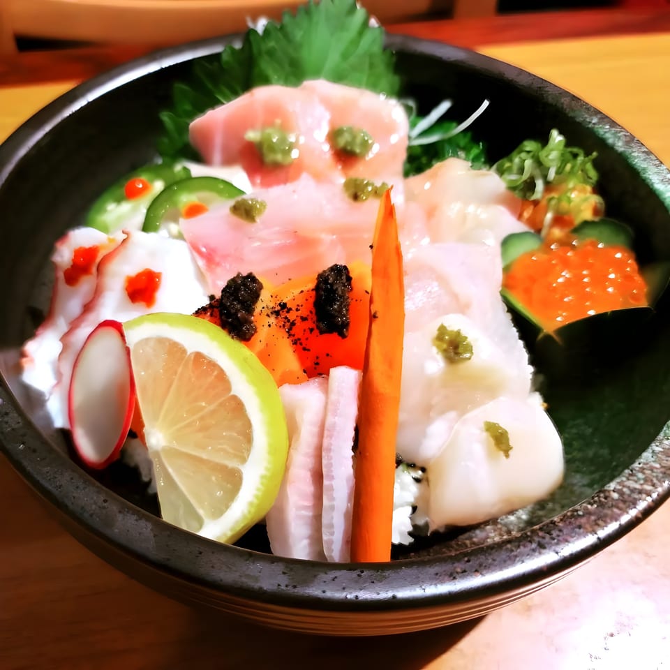 A colorful chirashi bowl from Sushi Goken, featuring various sashimi, roe, and garnishes.