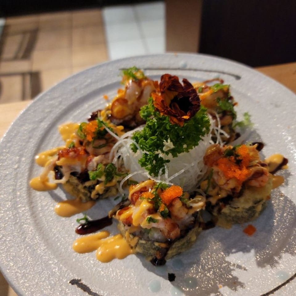 Sushi Goken's fried sushi rolls with sauce, roe, and a decorative flower on a white plate.