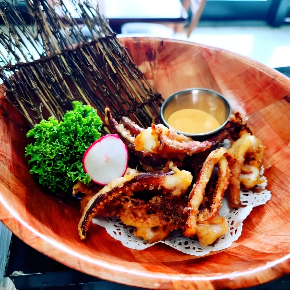 Crispy fried squid tentacles with lettuce, radish, and dipping sauce in a wooden bowl at Sushi Goken.
