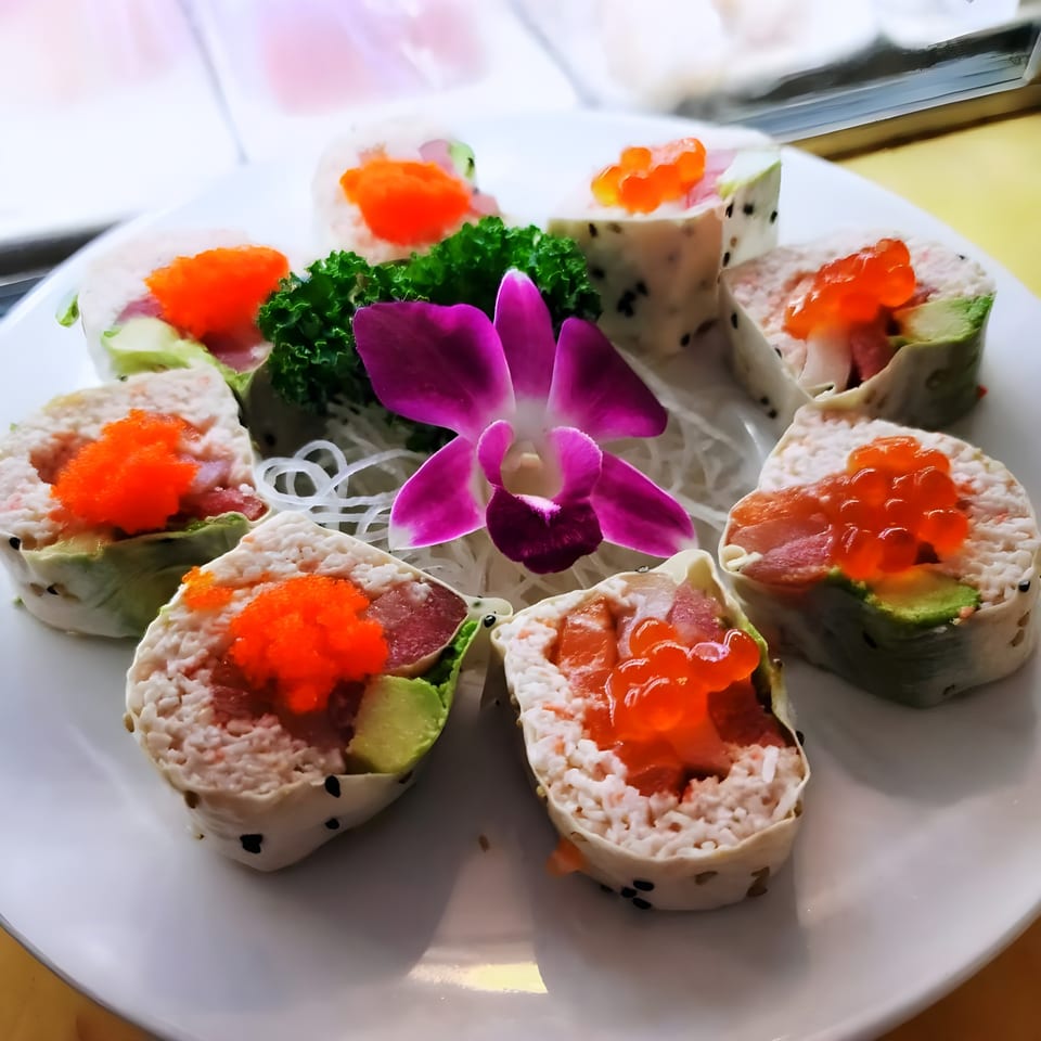Sushi Goken's colorful sushi rolls with bright orange roe, avocado, and tuna, garnished with a purple orchid.